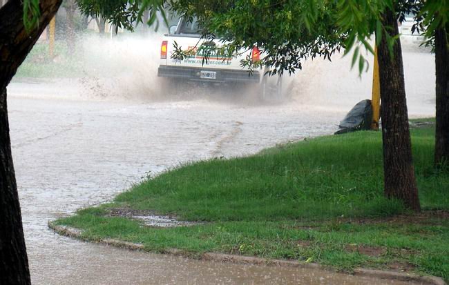 La camioneta transita por el centro de la calle, arrojando agua a ambas veredas.