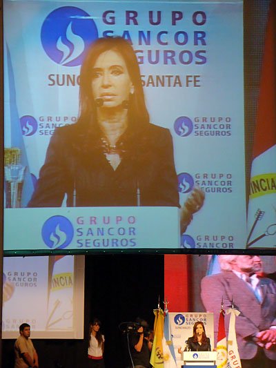 Cristina durante su discurso, reflejadas en pantallas gigantes dentro de la imponente carpa.